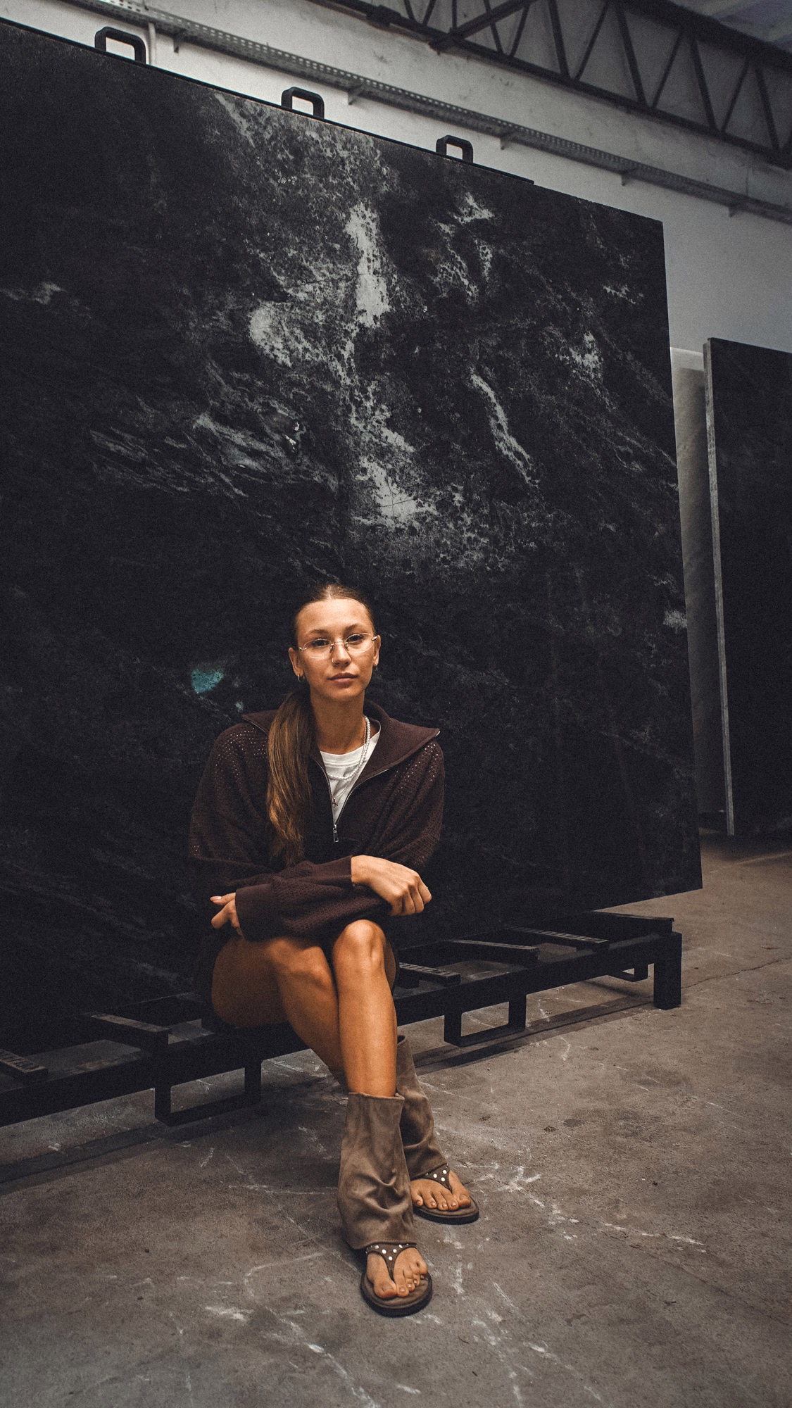 Kobieta siedzi przed ciemną płytą kamienia